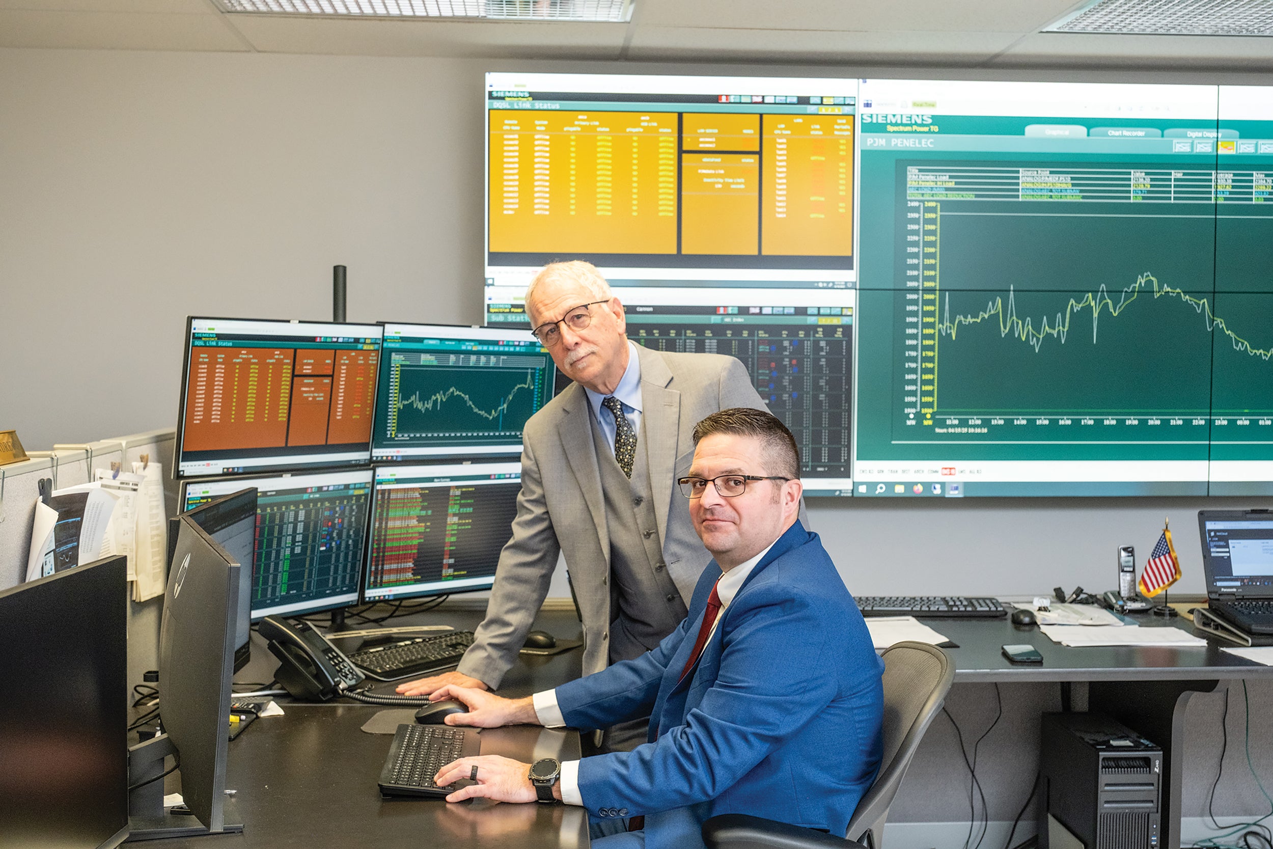 Tony Vincik, standing, PREA/Allegheny manager, energy management systems, and Brian Smith, PREA/Allegheny Coordinated Load Management System supervisor, review load forecasts to determine if it will be necessary to activate load control devices to reduce demand on the electric grid.