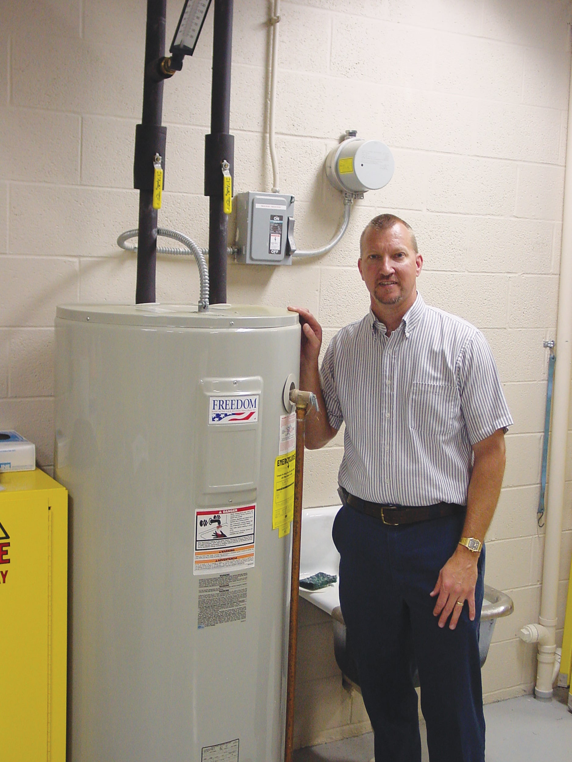 Brian Shearer, senior staff engineer at Gettysburg-based Adams Electric Cooperative, stands beside a water heater equipped with a load control receiver.