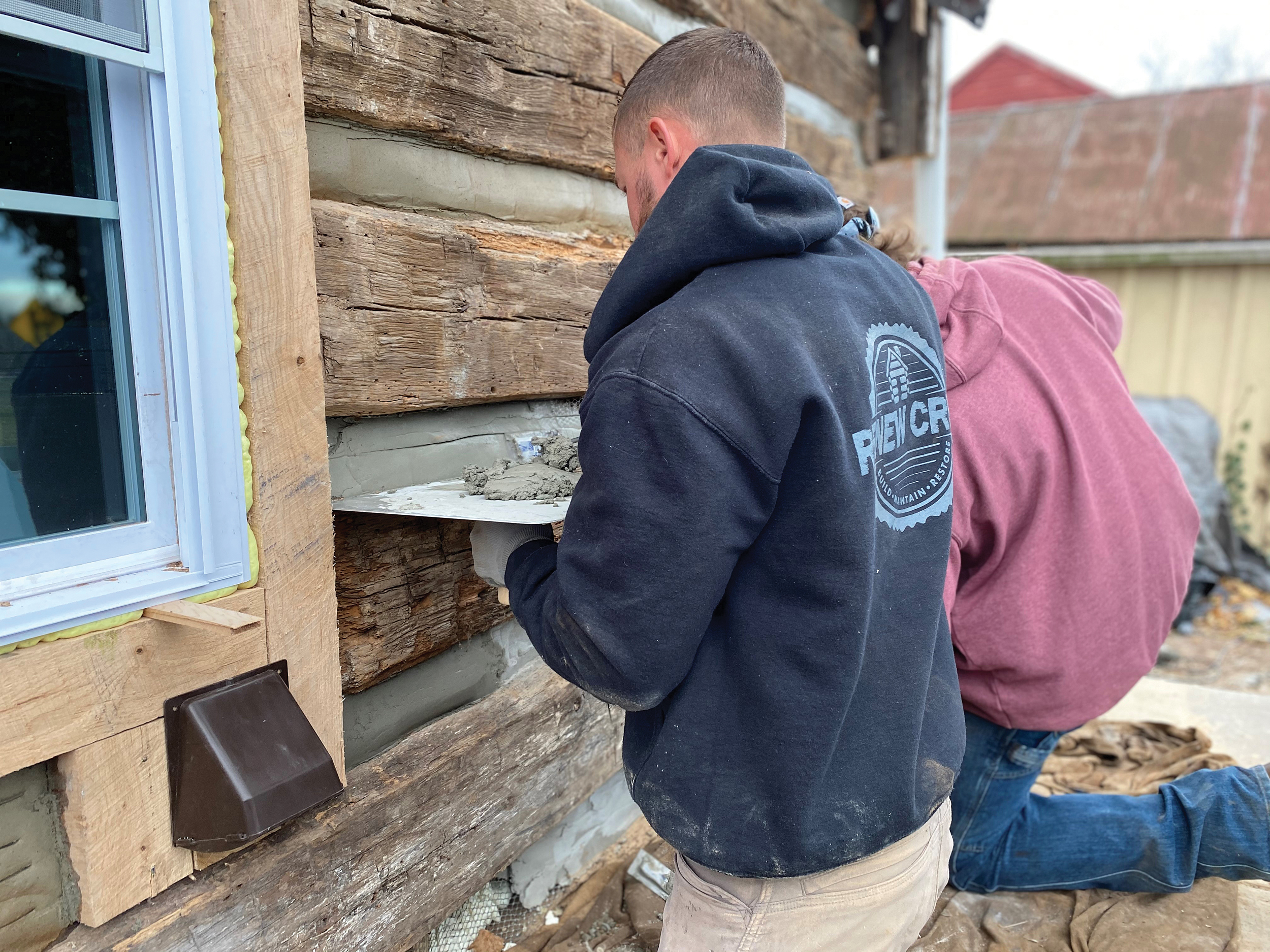 Crew members of Shippensburg-based Renew Services apply daubing to a log home in Gettysburg as part of a full restoration project.